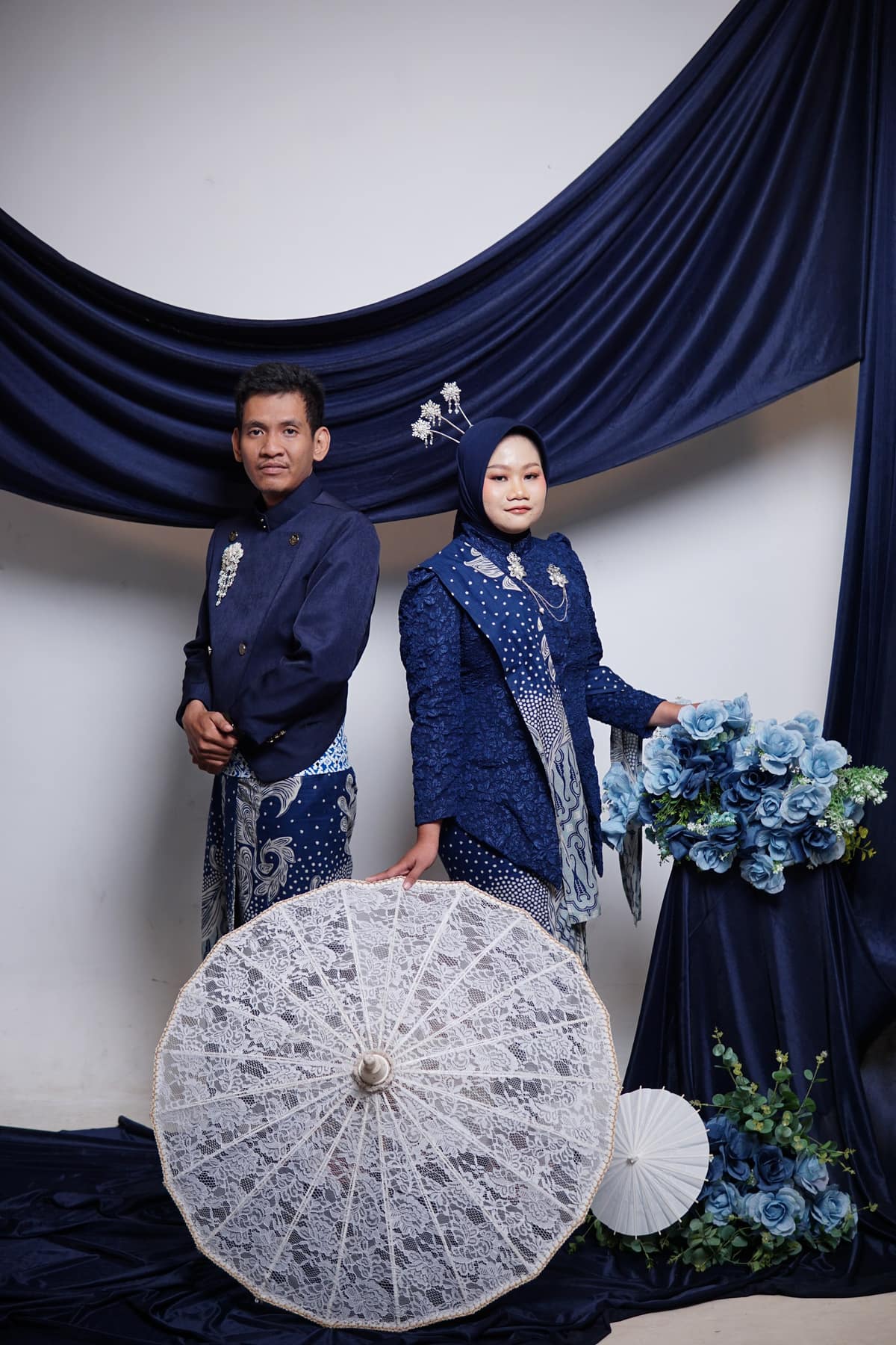 Dewi dan Fadli berdiri bersama dengan payung renda