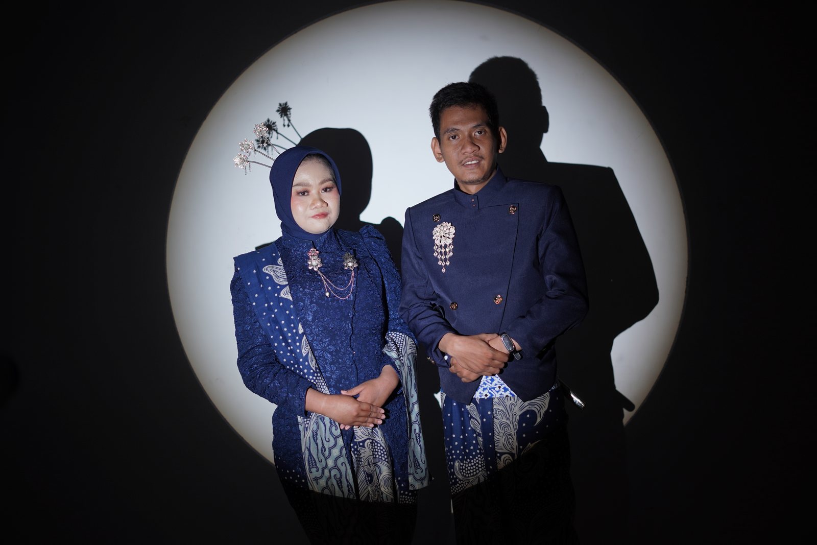Dewi dan Fadli saling menatap dalam busana biru di bawah lingkar cahaya