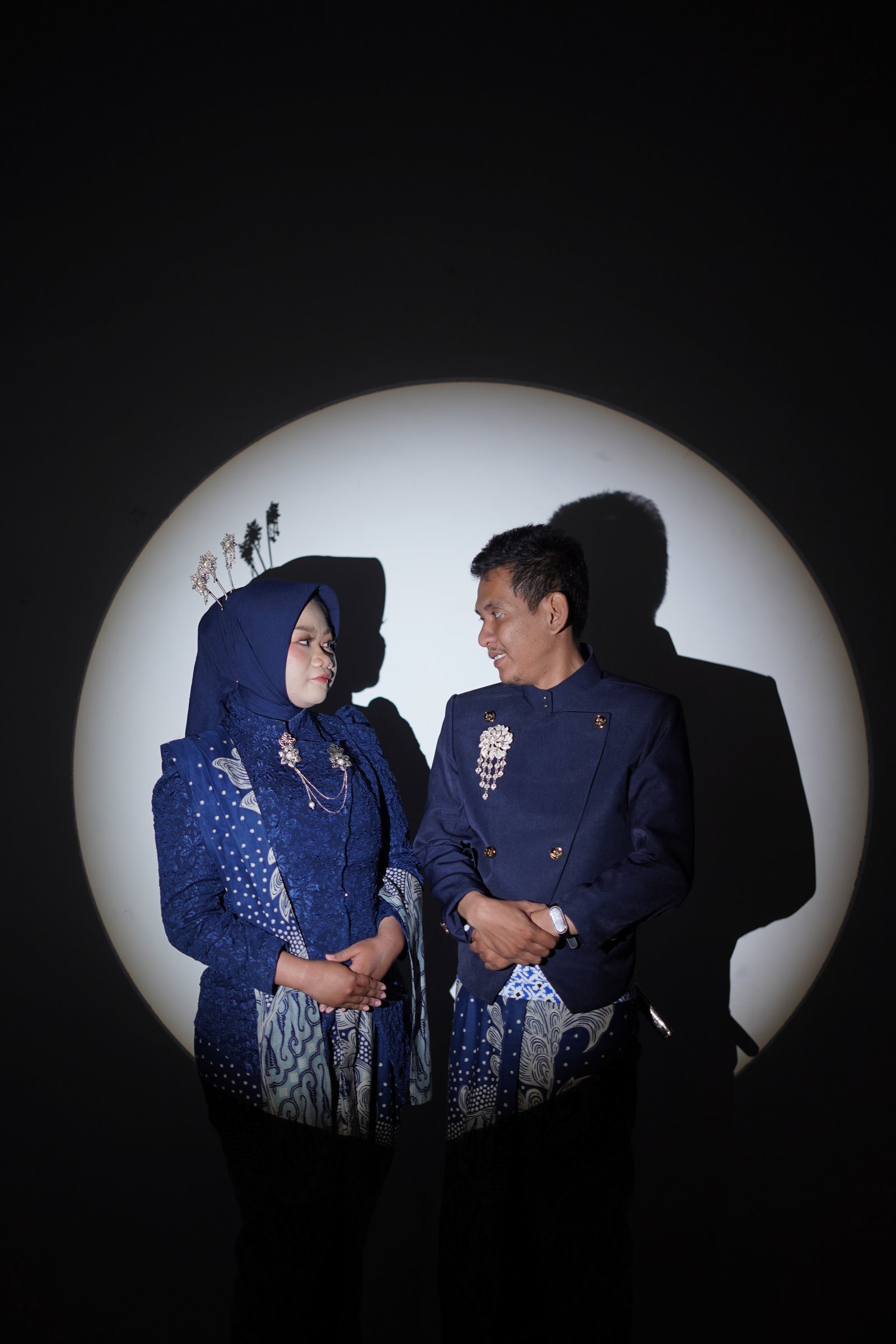 Dewi dan Fadli saling menatap dalam busana biru di bawah lingkar cahaya